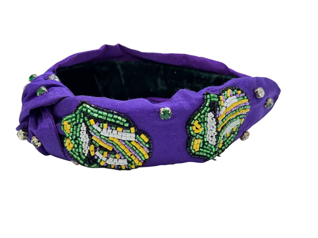 The Mardi Gras Green Tongue Beaded Knot Headband features green, yellow, white, and black patterns with rhinestone accents—an embellished festival hair accessory perfect for vibrant celebrations.