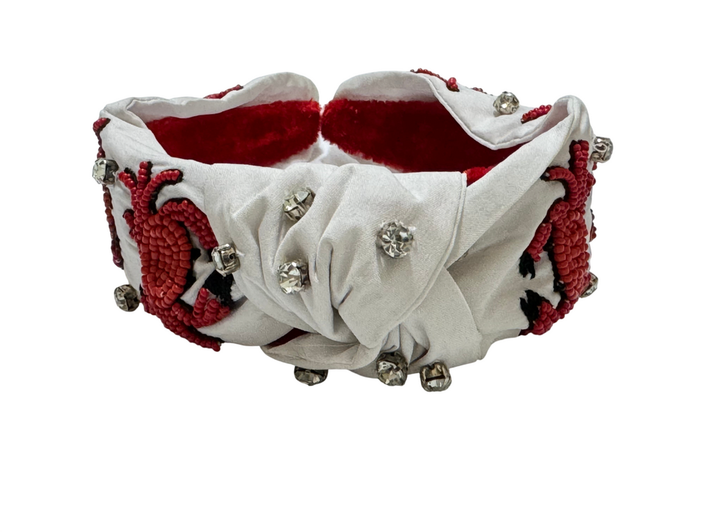 The Crab Headband is a beaded, ocean-themed statement headband featuring red crab designs and clear rhinestones. Lined with soft red velvet inside, this sea life beach hair accessory ensures comfortable wear.