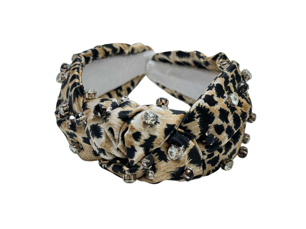 The Handcrafted Stylish Leopard and Cheetah Print Beaded Headband features a beige and black animal pattern, embellished with metallic studs and rhinestones, shown on a white background.
