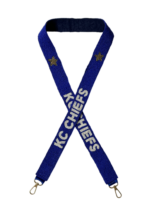 The KC Chiefs Gameday Beaded Purse Strap features a blue and white design with gold stars, white KC CHIEFS text on each side, and sturdy metal clips at both ends—perfect for football fans.